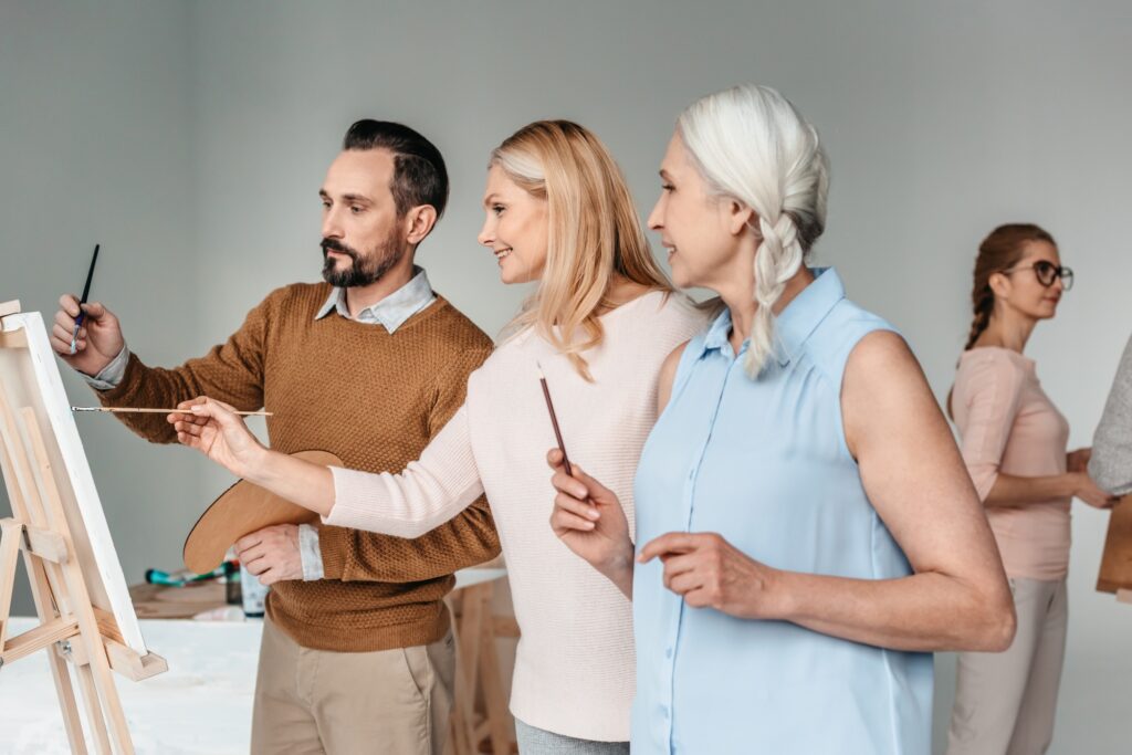 side view of mature artists painting together at art class